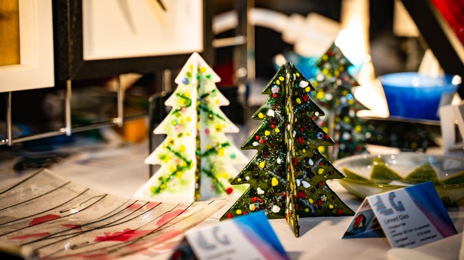 Two glass Christmas trees with other handmade glass objects including plates around them